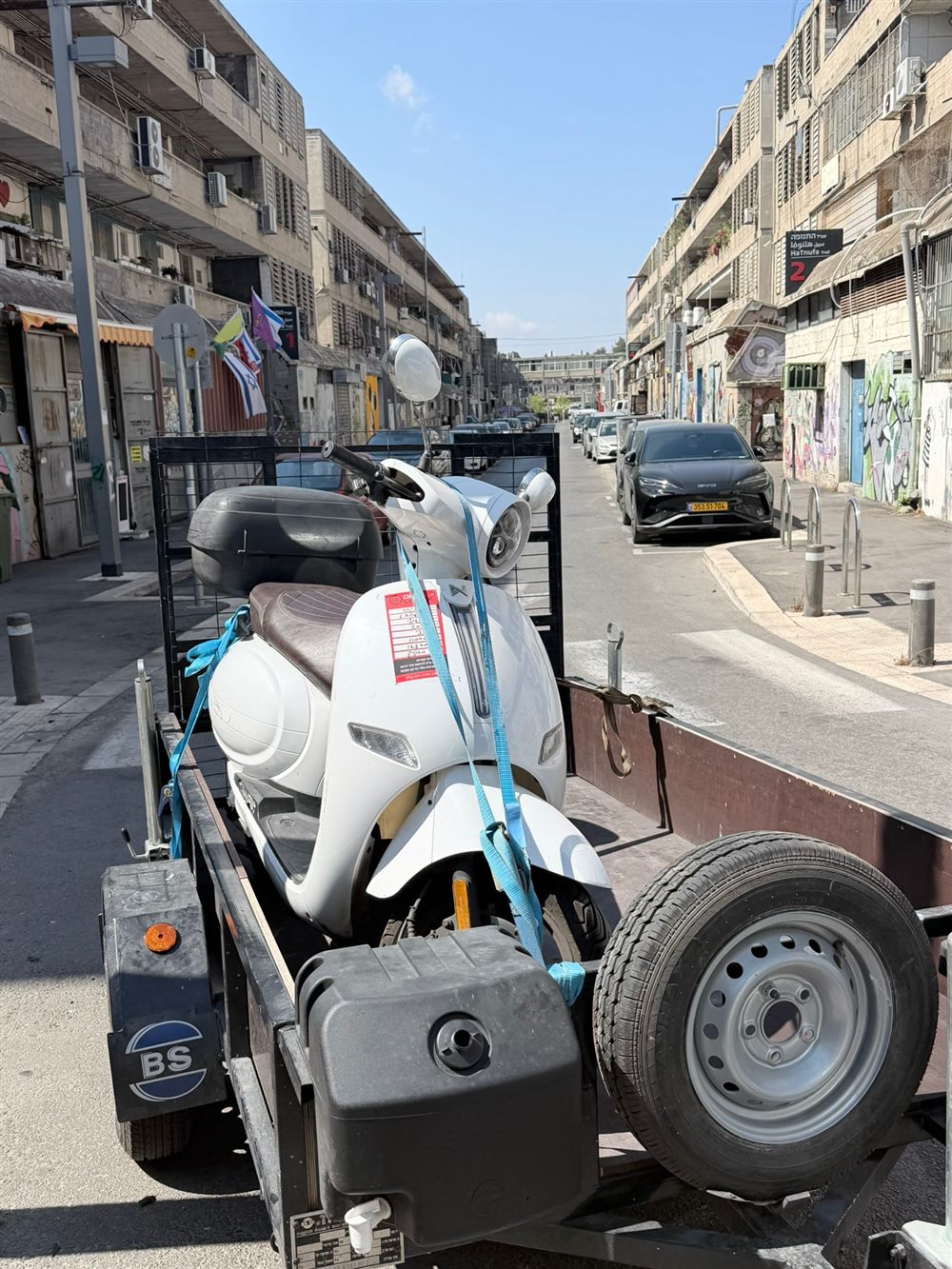 קטנוע לבן קשור על הגרר ברחוב עירוני